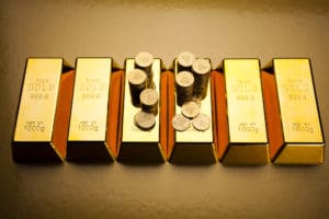 Gold coins sit upon a series of gold bars.