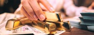 The hand holding the precious gold bar shows the success of the finance business