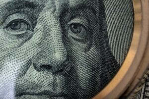 Close-up portrait of Ben Franklin on US 100 dollar bill under a magnifying glass. American banknote