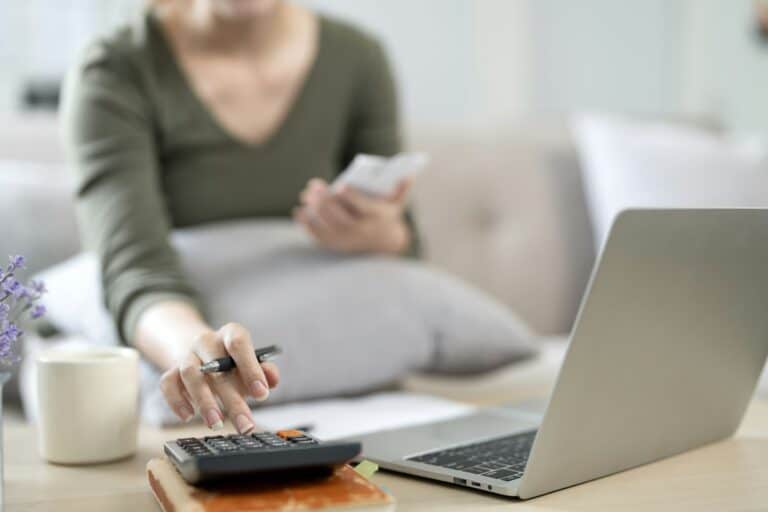 Close up of woman using calculator paying bills online, calculating household finances.