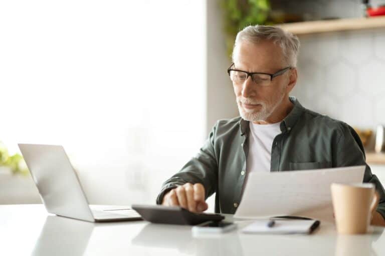 Retirement And Finances. Smiling Senior Gentleman Calculating Taxes At Home