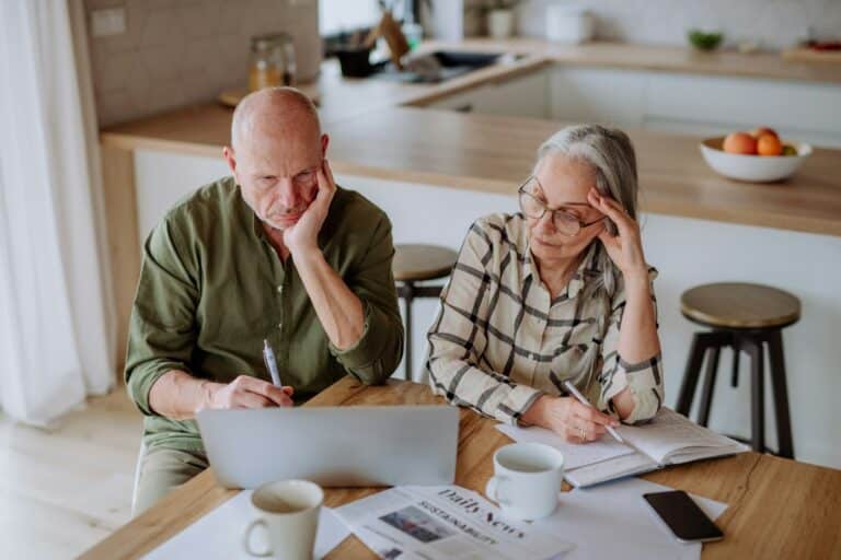 Stressed senior couple calculate expenses or planning budget together at home.