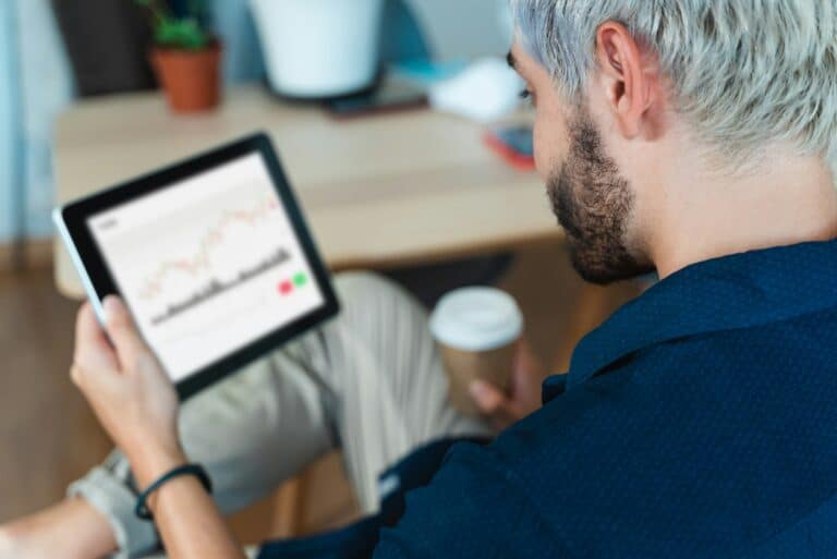 Young trader man doing stock analysis research on computer tablet inside startup office